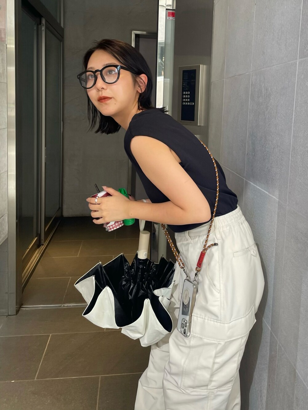 ブラック系のニット/セーター、ホワイト系のカーゴパンツを着用したレディースの夏コーディネートの2枚目の写真