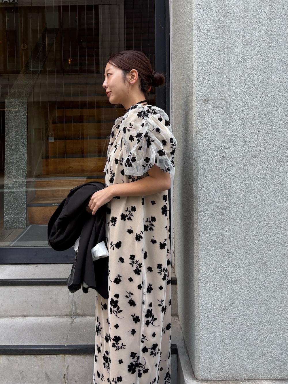 ベージュ系のワンピース、ブラック系のテーラードジャケット、ブラック系のパンプスを着用したレディースの春コーディネートの2枚目の写真