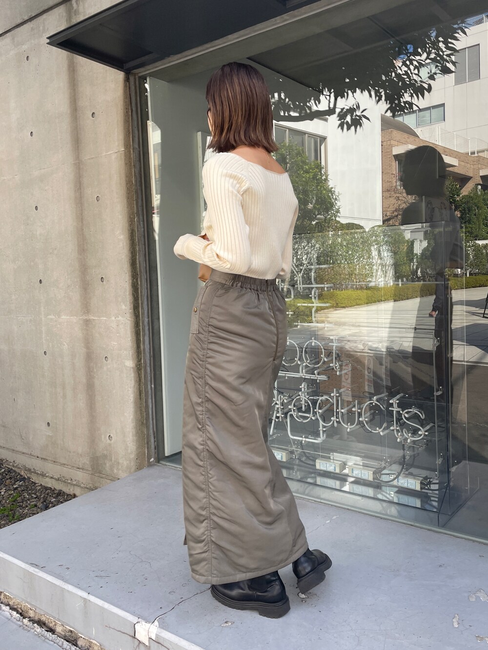 グリーン系のスカート、ホワイト系のニット/セーターを着用したレディースの秋コーディネートの2枚目の写真