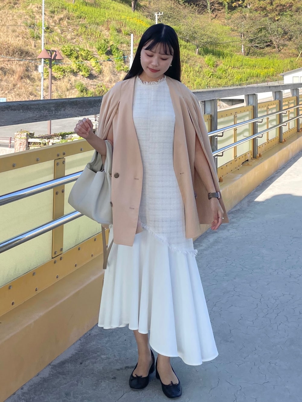 ベージュ系のテーラードジャケット、ホワイト系のワンピース、ブラック系のパンプスを着用したレディースの秋コーディネートの2枚目の写真