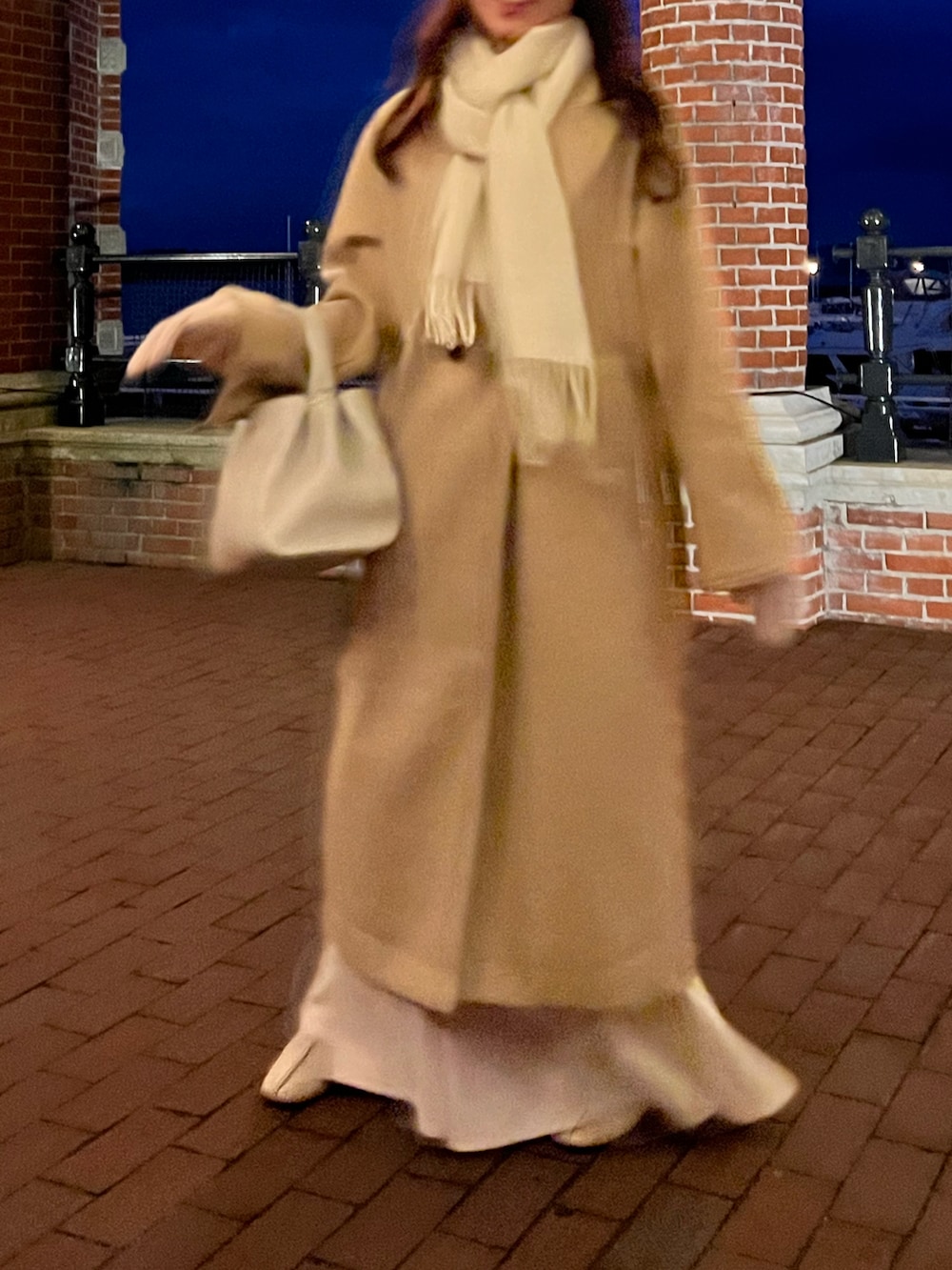 ベージュ系のチェスターコート、ホワイト系のハンドバッグ、ベージュ系のブーツを着用したレディースの冬コーディネートの3枚目の写真