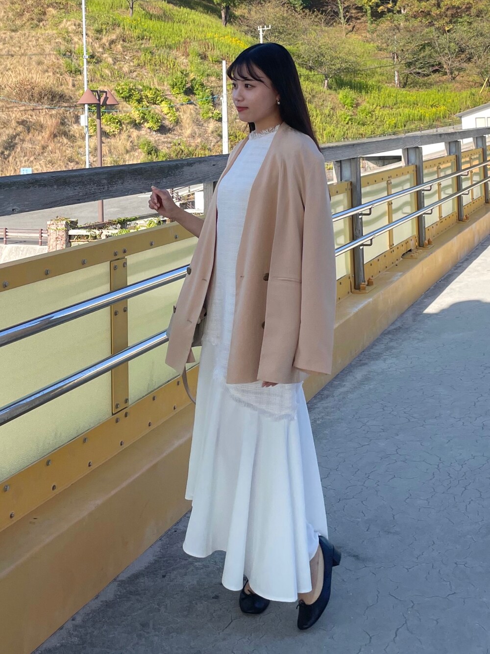 ベージュ系のテーラードジャケット、ホワイト系のワンピース、ブラック系のパンプスを着用したレディースの秋コーディネートの3枚目の写真