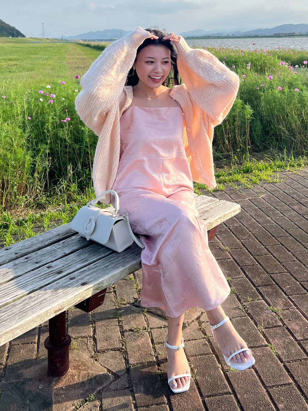 ピンク系のカーディガン/ボレロ、ピンク系のワンピース、ホワイト系のサンダルを着用したレディースの秋コーディネートの2枚目の写真