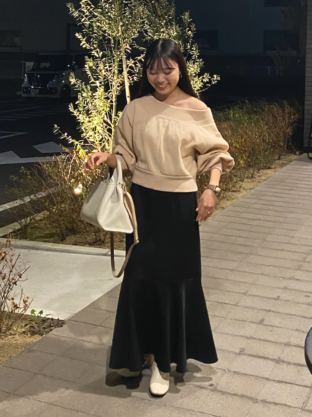 ホワイト系のハンドバッグ、ブラック系のスカート、ホワイト系のブーツを着用したレディースの秋コーディネートの2枚目の写真