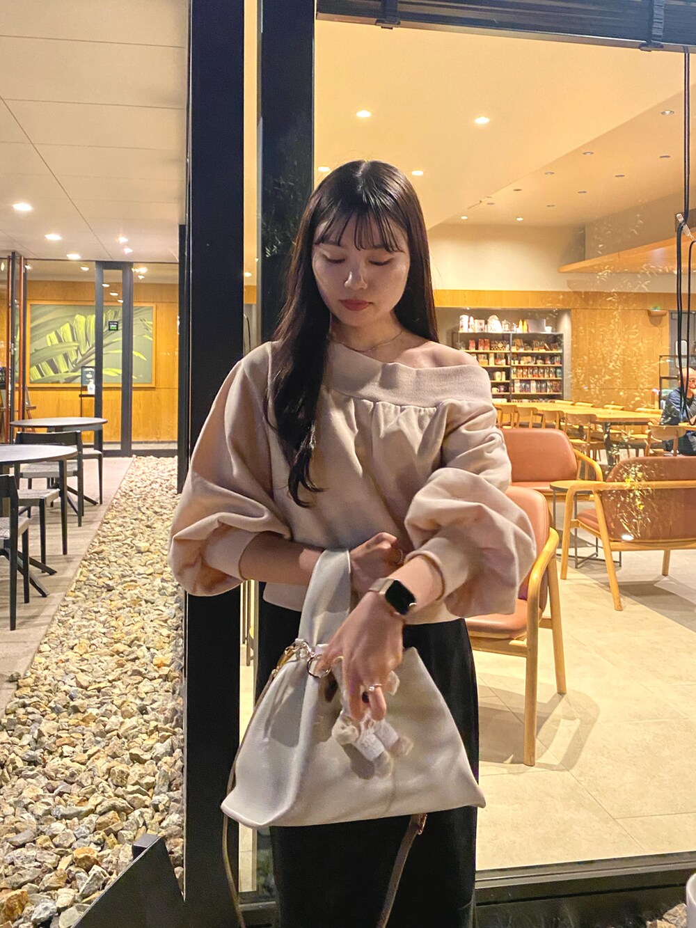 ホワイト系のハンドバッグ、ブラック系のスカート、ホワイト系のブーツを着用したレディースの秋コーディネートの3枚目の写真