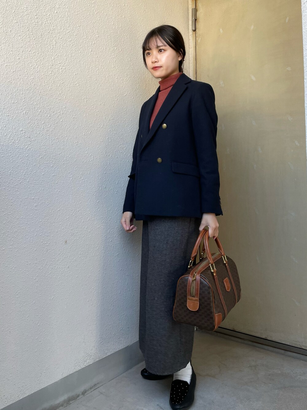 ブラウン系のボストンバッグ、ブラウン系のスカート、ブルー系のテーラードジャケットを着用したレディースの春コーディネートの2枚目の写真