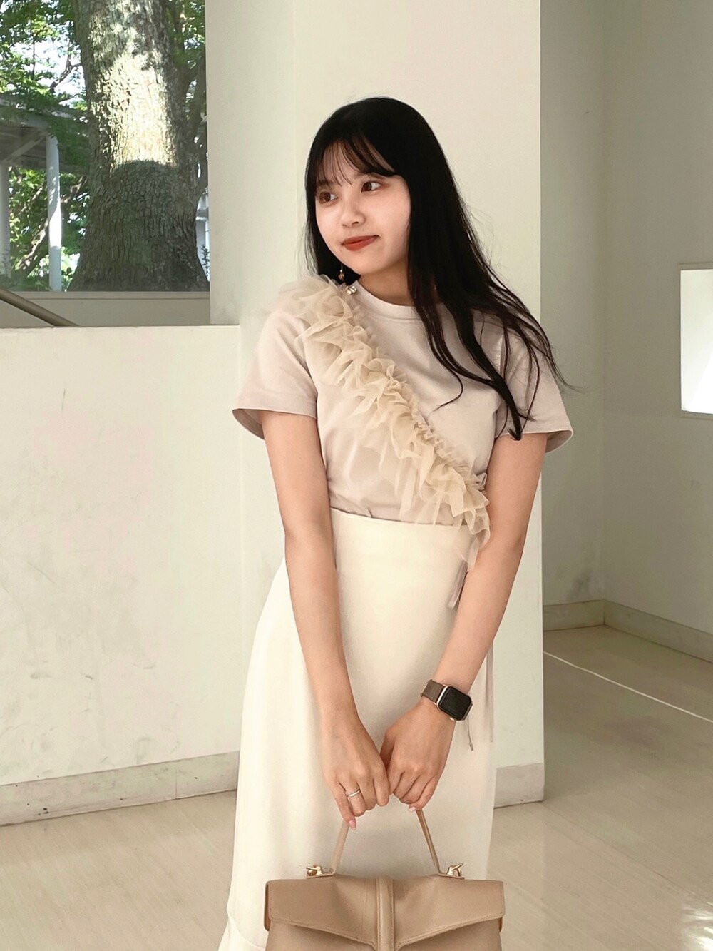 ベージュ系のハンドバッグ、ホワイト系のスカート、ベージュ系のTシャツ/カットソーを着用したレディースの夏コーディネートの3枚目の写真