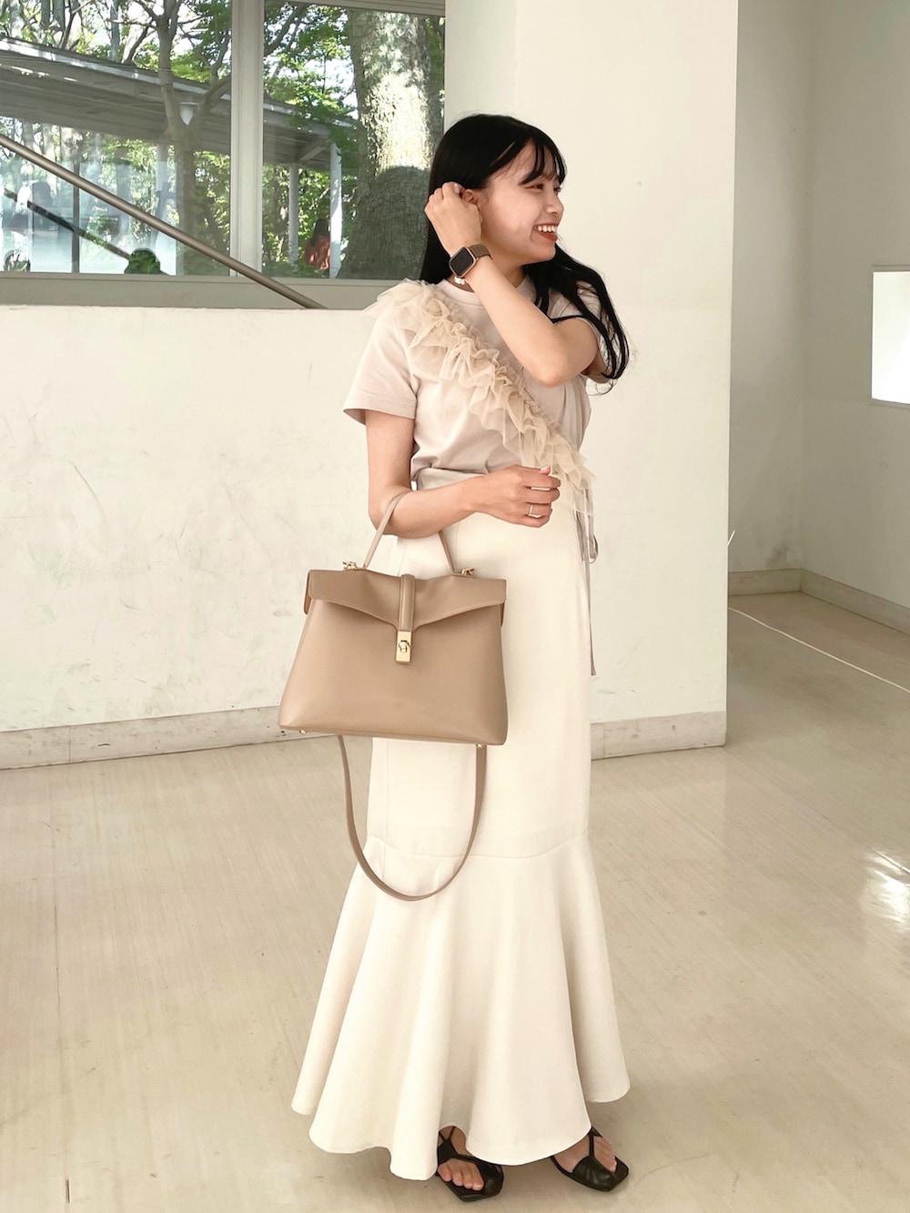 ベージュ系のハンドバッグ、ホワイト系のスカート、ベージュ系のTシャツ/カットソーを着用したレディースの夏コーディネートの2枚目の写真