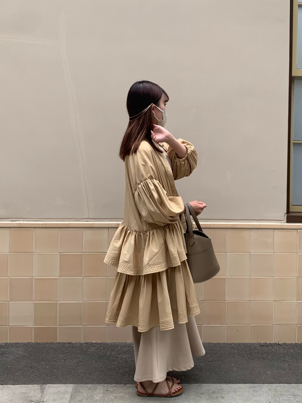 ベージュ系のショルダーバッグ、ベージュ系のスカート、ブラウン系のサンダルを着用したレディースの冬コーディネートの2枚目の写真