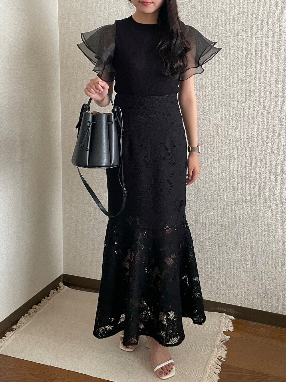 ブラック系のハンドバッグ、ブラック系のスカート、ホワイト系のサンダルを着用したレディースの夏コーディネートの3枚目の写真