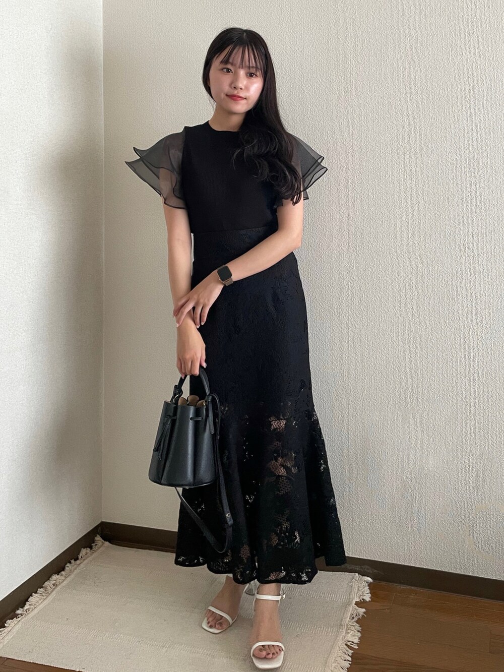 ブラック系のハンドバッグ、ブラック系のスカート、ホワイト系のサンダルを着用したレディースの夏コーディネートの2枚目の写真