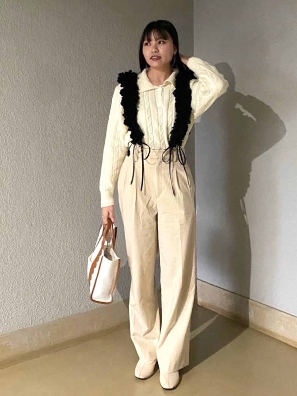 ホワイト系のトートバッグ、ホワイト系のニット/セーター、ベージュ系のその他パンツを着用したレディースの冬コーディネートの2枚目の写真
