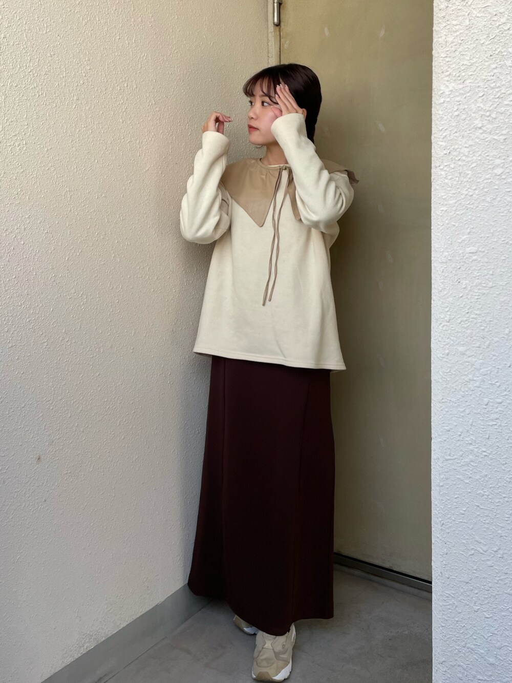 イエロー系のトップス、ブラウン系のワンピース、ベージュ系のスニーカーを着用したレディースの冬コーディネートの2枚目の写真