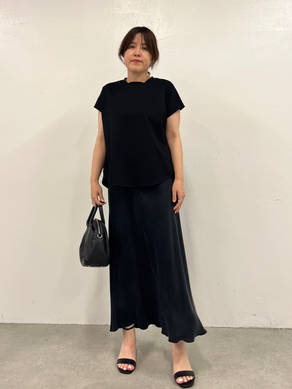 ブラック系のスカート、ブラック系のTシャツ/カットソーを着用したレディースの春コーディネートの6枚目の写真