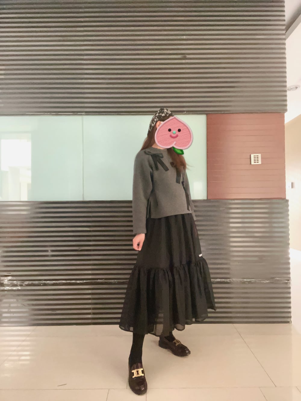 グレー系のパーカー、ブラック系のスカート、ブラウン系のローファーを着用したレディースの秋コーディネートの2枚目の写真