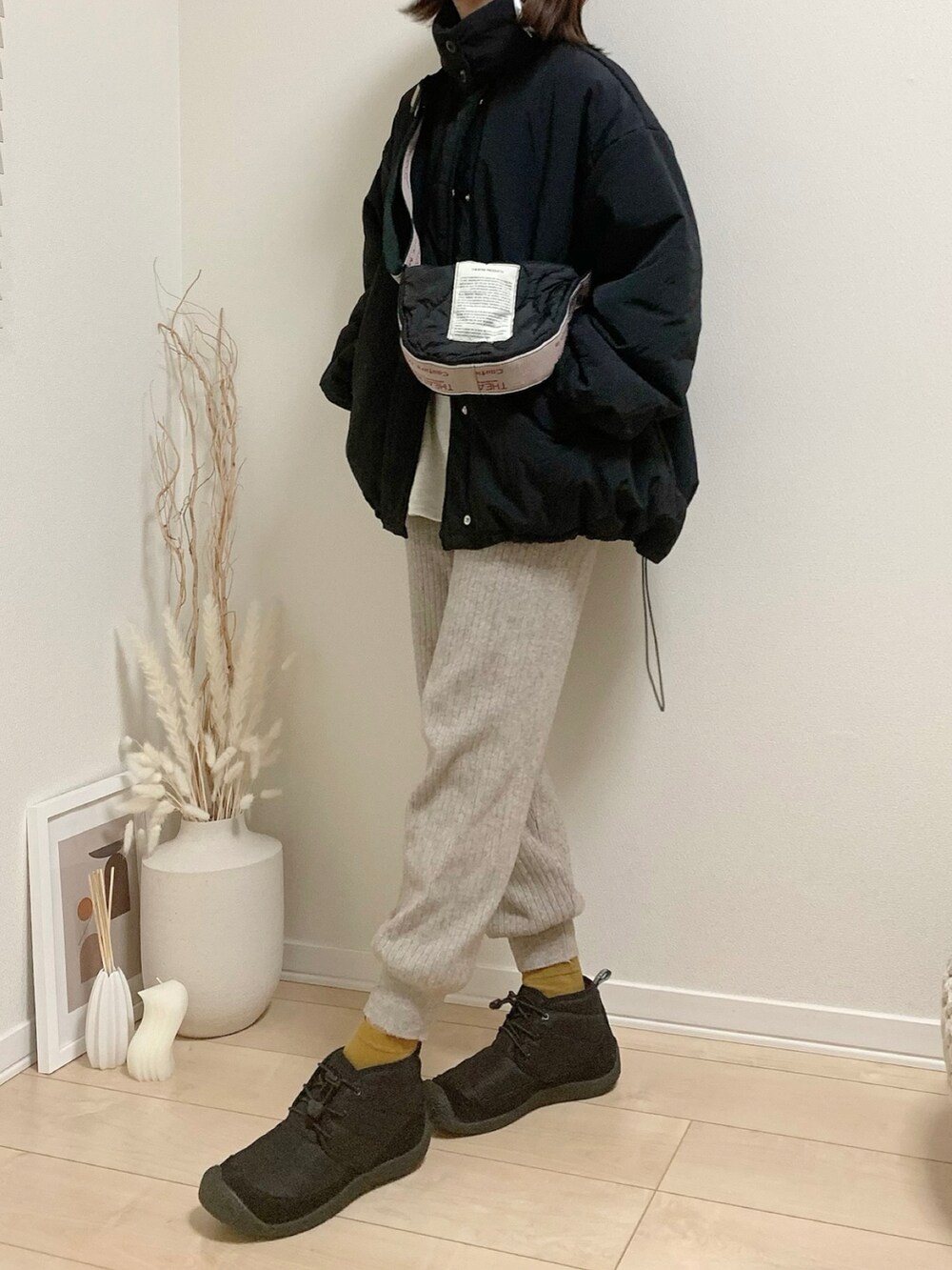 ブラック系のブルゾン、ブラック系のブーツ、ブラック系のショルダーバッグを着用したレディースの冬コーディネートの2枚目の写真