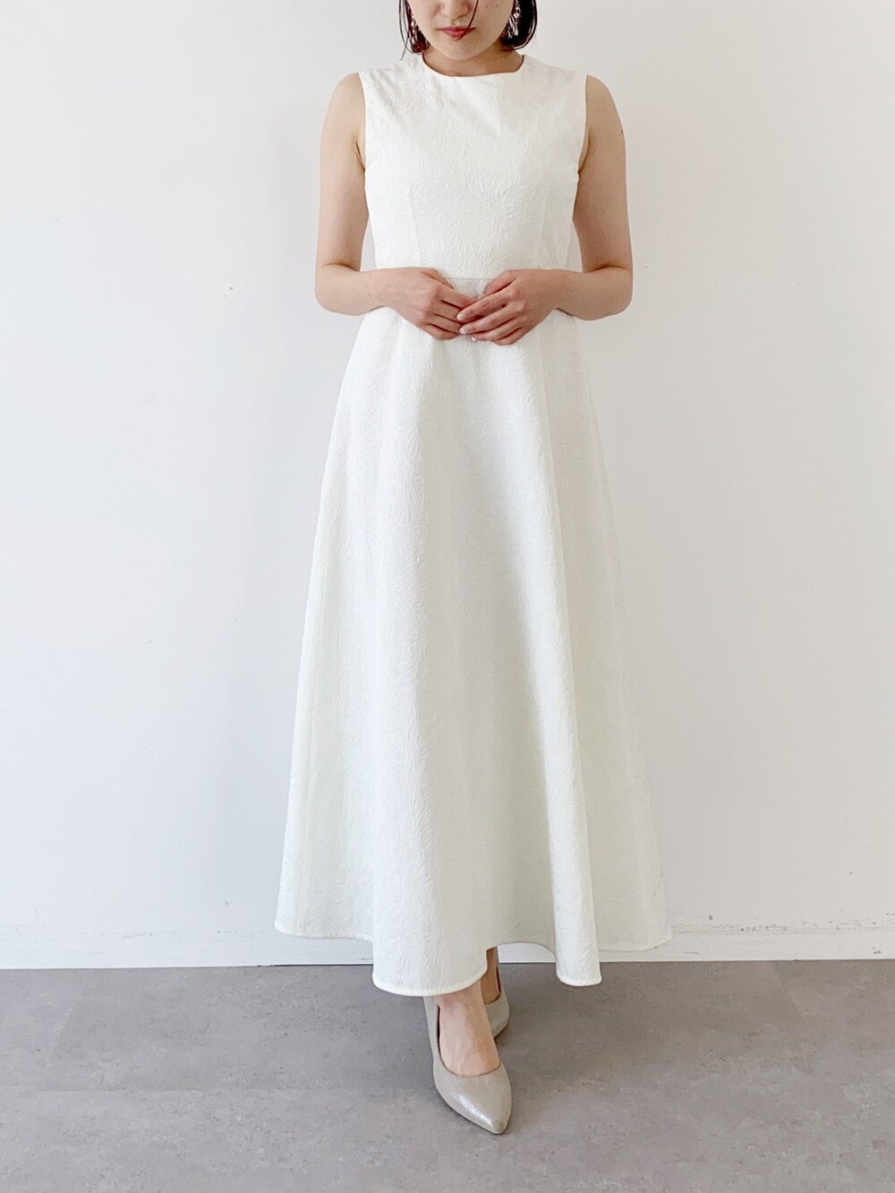 ホワイト系のドレス、ホワイト系のカーディガン/ボレロ、ホワイト系のピアス（両耳用）を着用したレディースの夏コーディネートの2枚目の写真