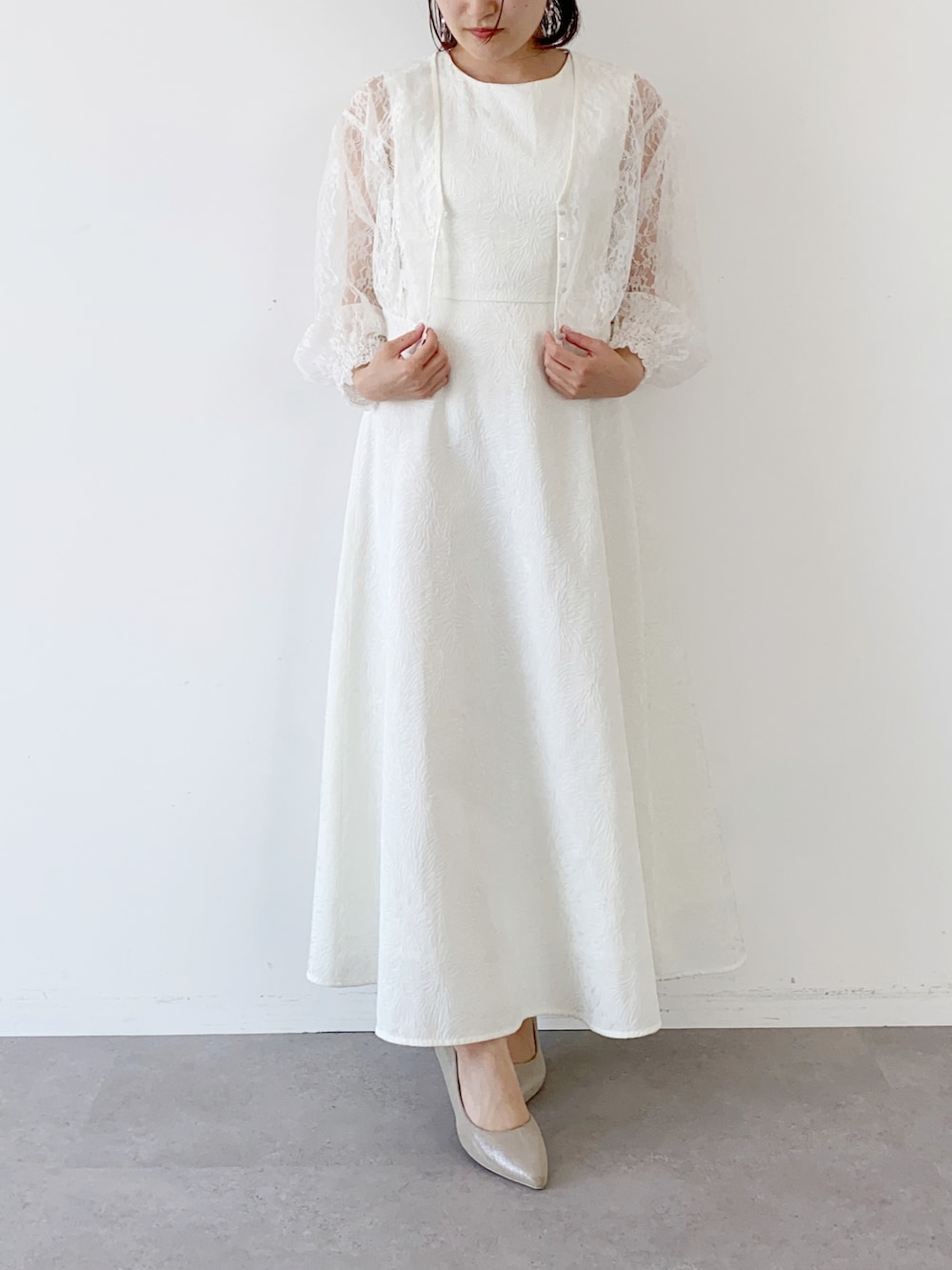 ホワイト系のドレス、ホワイト系のカーディガン/ボレロ、ホワイト系のピアス（両耳用）を着用したレディースの夏コーディネートの3枚目の写真