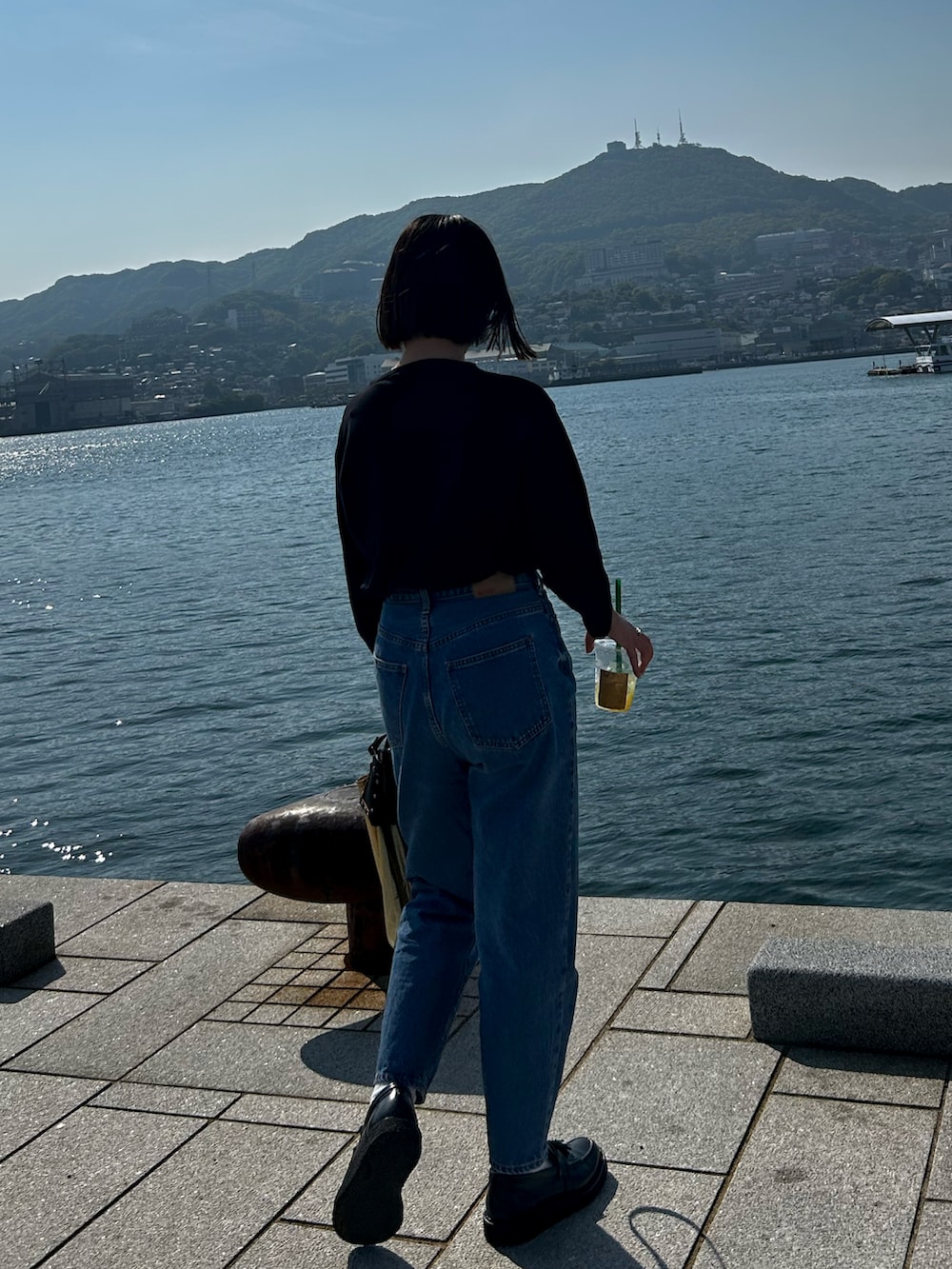 ブラック系のTシャツ/カットソー、ブルー系のデニムパンツ、ブラック系のショルダーバッグを着用したレディースの春コーディネートの2枚目の写真