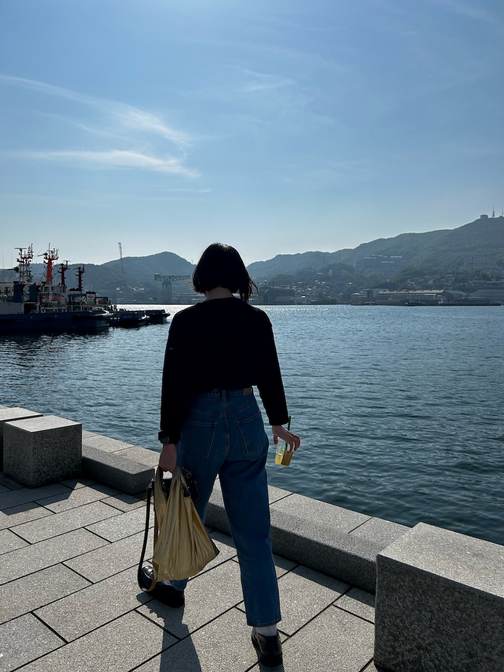 ブラック系のTシャツ/カットソー、ブルー系のデニムパンツ、ブラック系のショルダーバッグを着用したレディースの春コーディネートの3枚目の写真