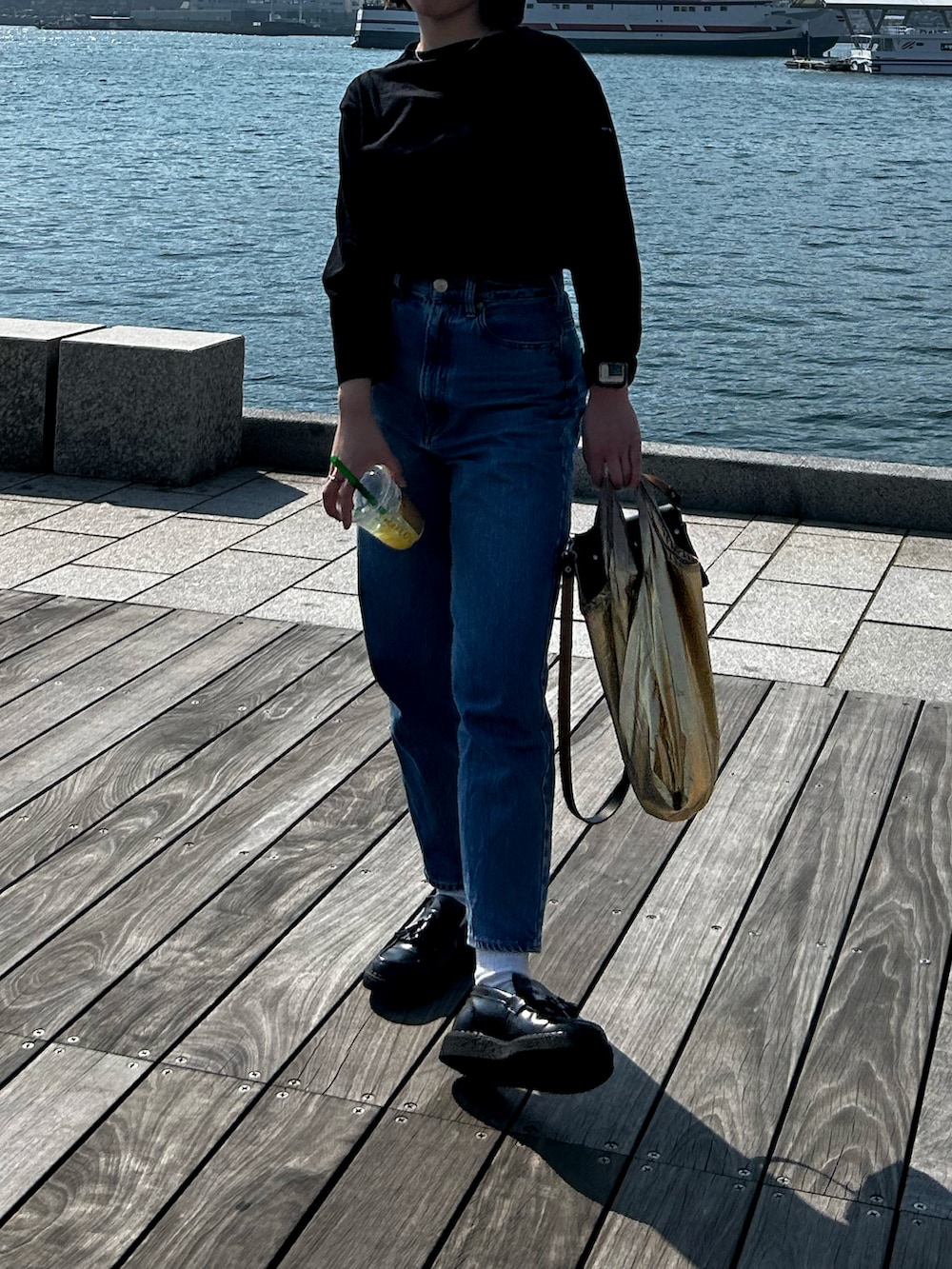 ブラック系のTシャツ/カットソー、ブルー系のデニムパンツ、ブラック系のショルダーバッグを着用したレディースの春コーディネートの5枚目の写真