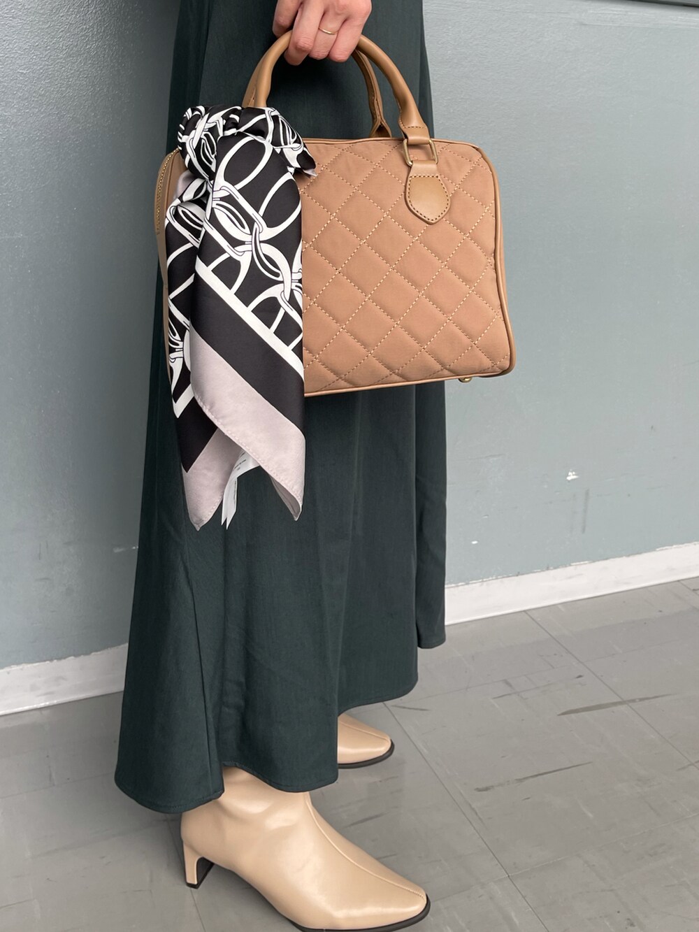 ベージュ系のハンドバッグ、グレー系のTシャツ/カットソー、グリーン系のスカートを着用したレディースの秋コーディネートの4枚目の写真