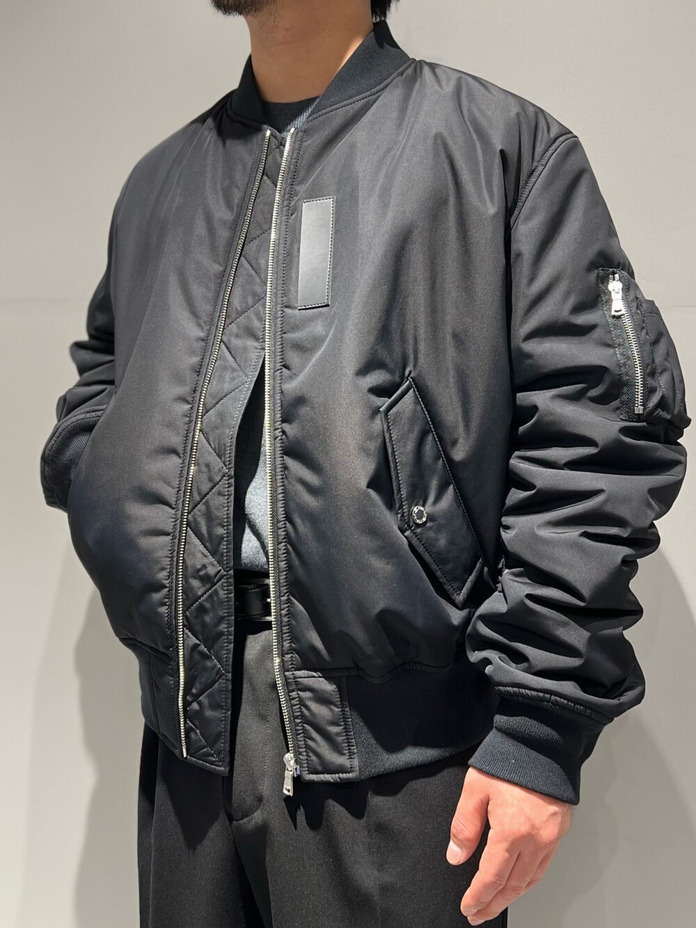 ブラック系のスラックス、グレー系のニット/セーター、ブラック系のMA-1を着用したメンズの秋コーディネートの2枚目の写真