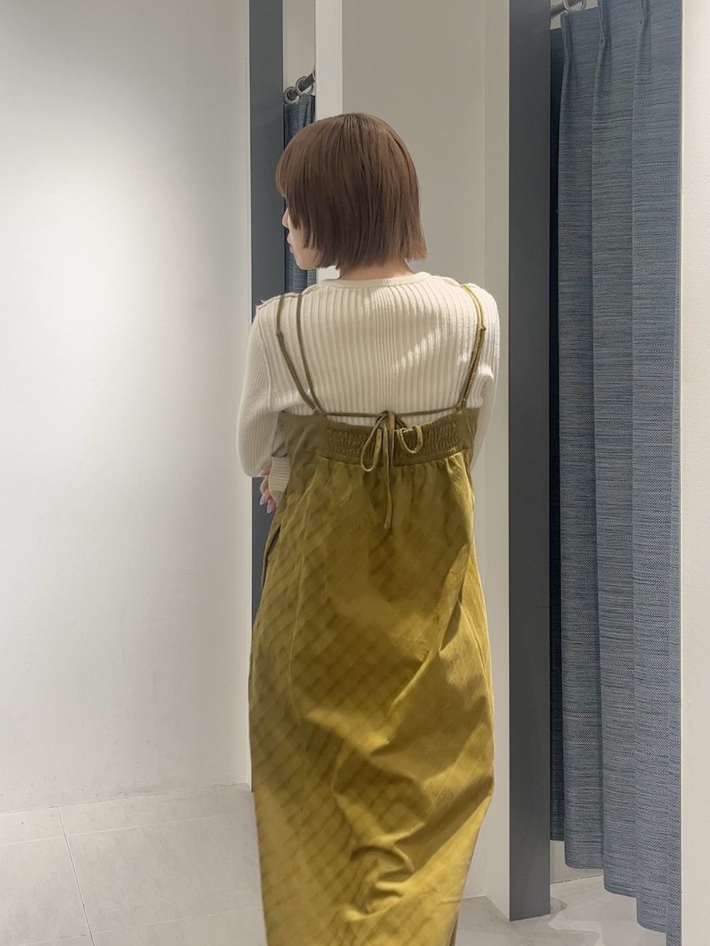 ホワイト系のニット/セーター、ブラウン系のカバーオール、イエロー系のワンピースを着用したレディースの秋コーディネートの4枚目の写真