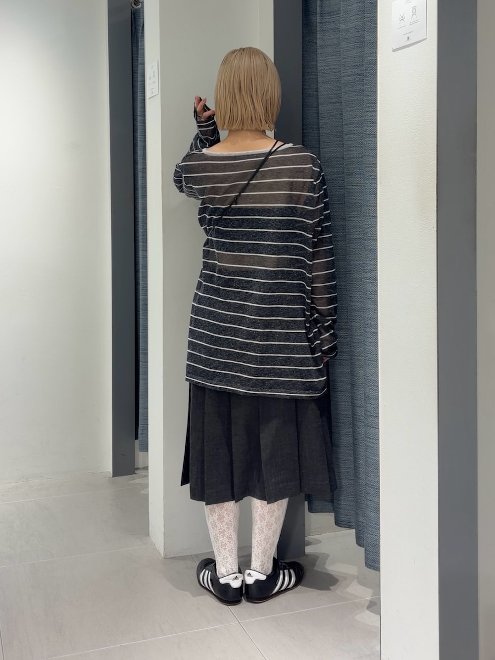 グレー系のニット/セーター、グレー系のスカート、ブラック系のスニーカーを着用したレディースの秋コーディネートの2枚目の写真