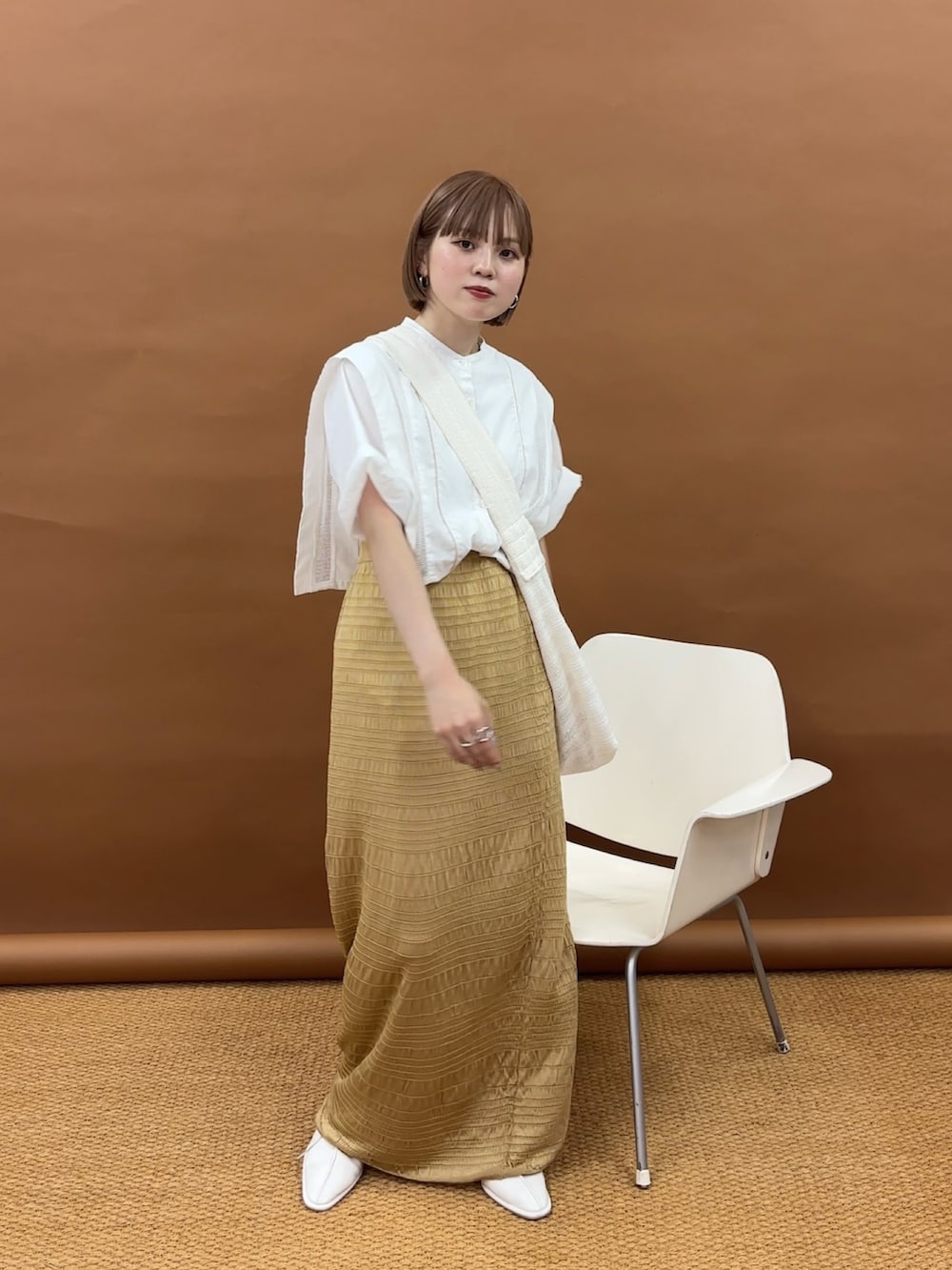 ゴールド系のスカート、ホワイト系のその他シューズ、ホワイト系のシャツ/ブラウスを着用したレディースの夏コーディネートの3枚目の写真