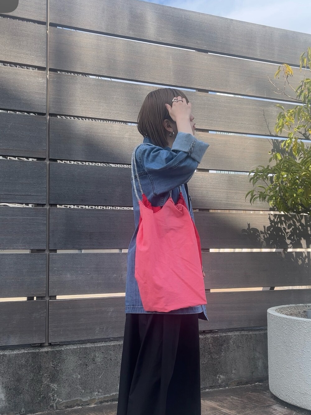 ピンク系のトートバッグ、ブルー系のデニムジャケット、グレー系のワンピースを着用したレディースの春コーディネートの2枚目の写真