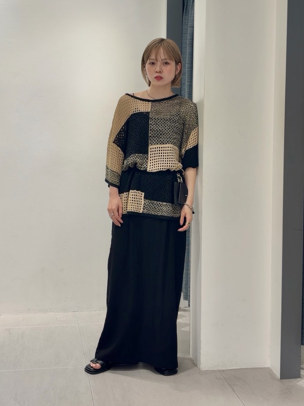 ベージュ系のニット/セーター、ブラック系のショルダーバッグ、ブラック系のセットアップを着用したレディースの夏コーディネートの3枚目の写真