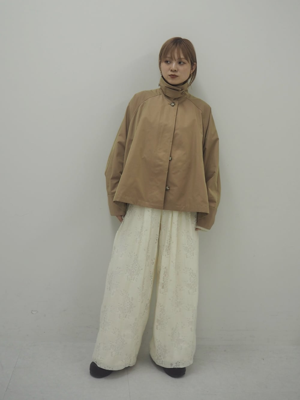 ベージュ系のステンカラーコート、ホワイト系のその他パンツ、ブラウン系のその他シューズを着用したレディースの冬コーディネートの6枚目の写真