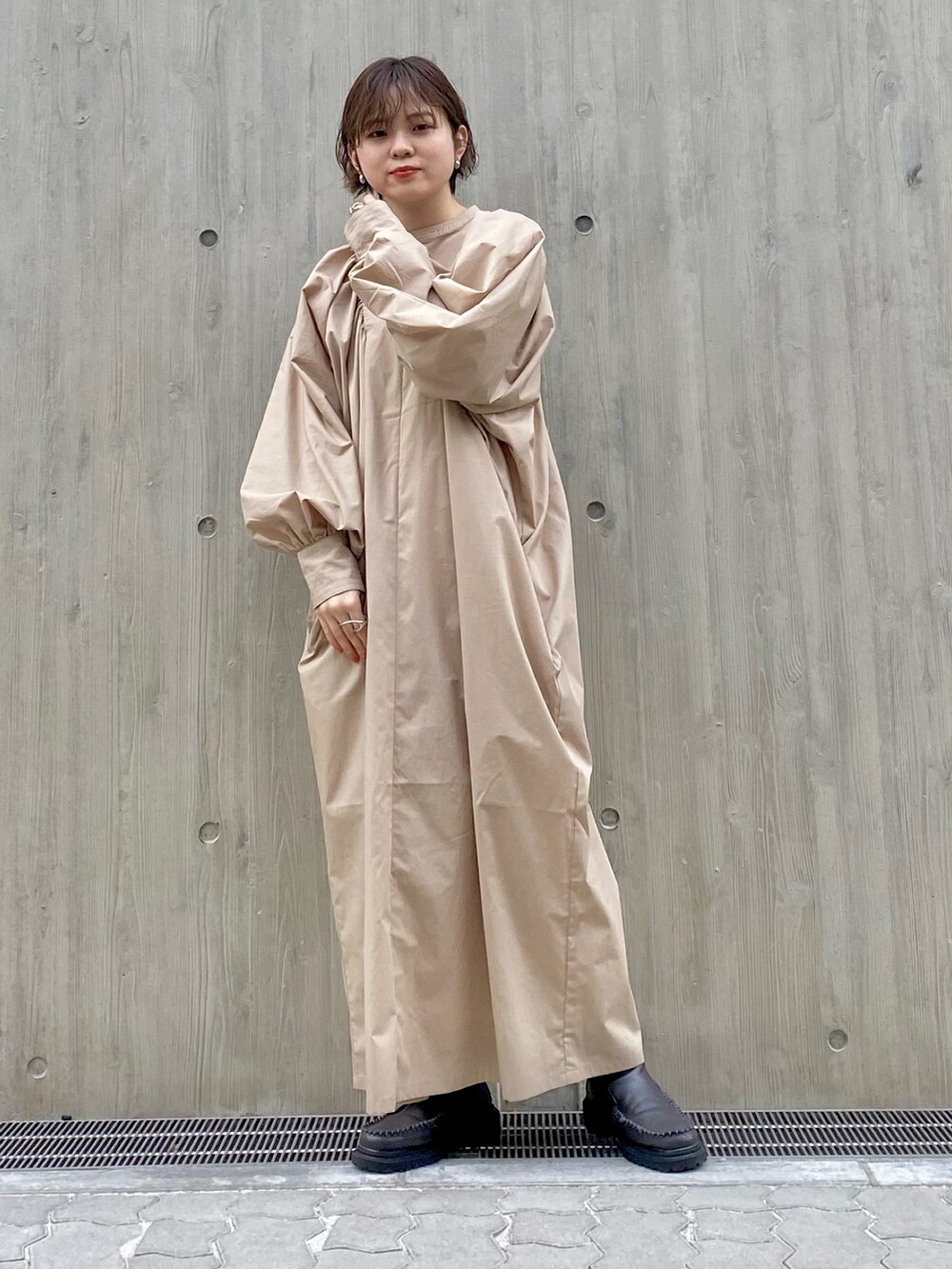 グレー系のブーツ、ベージュ系のワンピース、ピンク系のカーディガン/ボレロを着用したレディースの春コーディネートの2枚目の写真