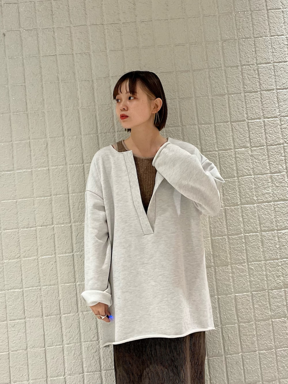 ブラウン系のピーコート、ベージュ系のTシャツ/カットソー、ブラウン系のタンクトップを着用したレディースの冬コーディネートの3枚目の写真