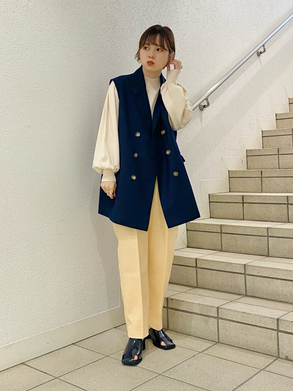 イエロー系のサンダル、イエロー系のその他パンツ、ブルー系のベストを着用したレディースの春コーディネートの4枚目の写真