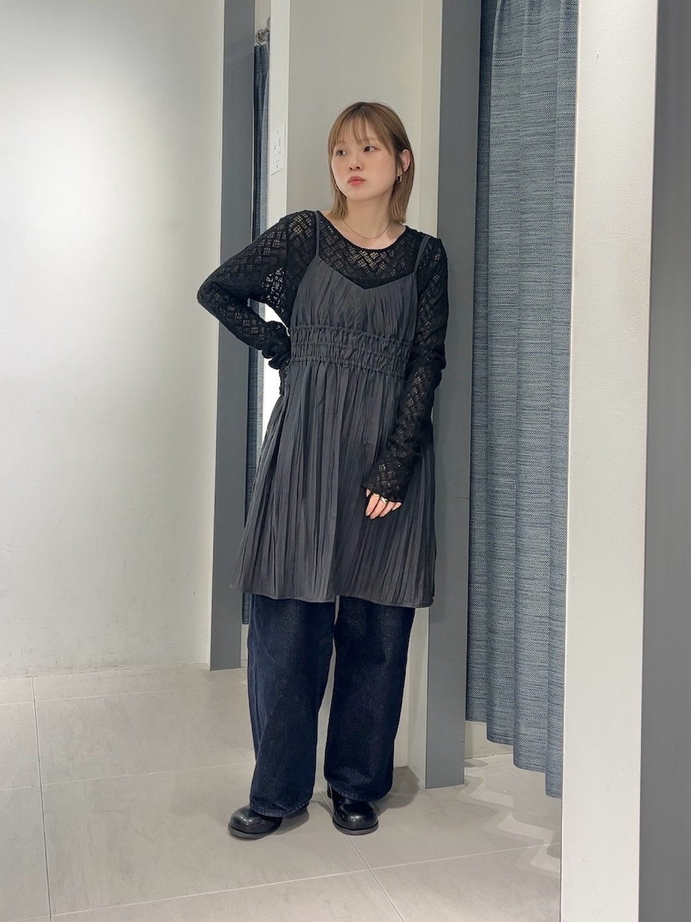 グレー系のワンピース、ブルー系のデニムパンツ、ブラック系のサンダルを着用したレディースの春コーディネートの2枚目の写真