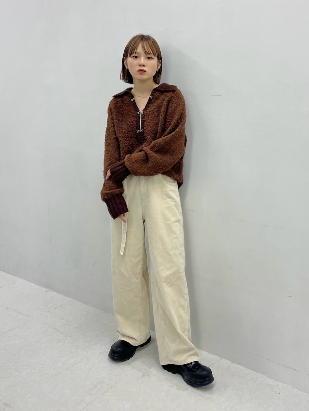 ブラウン系のニット/セーター、ブラック系のブーツ、ホワイト系のその他パンツを着用したレディースの秋コーディネートの3枚目の写真