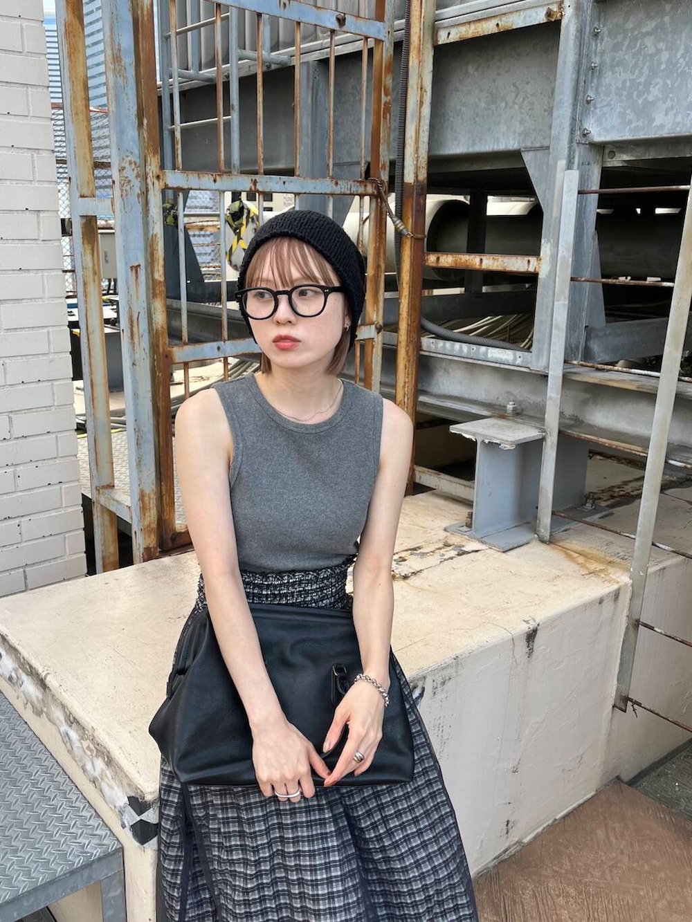グレー系のタンクトップ、ブラック系のスカート、ブラック系のボストンバッグを着用したレディースの夏コーディネートの3枚目の写真