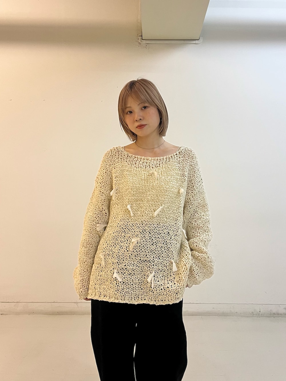 ホワイト系のニット/セーター、ホワイト系のキャミソール、ブラック系のデニムパンツを着用したレディースの冬コーディネートの3枚目の写真