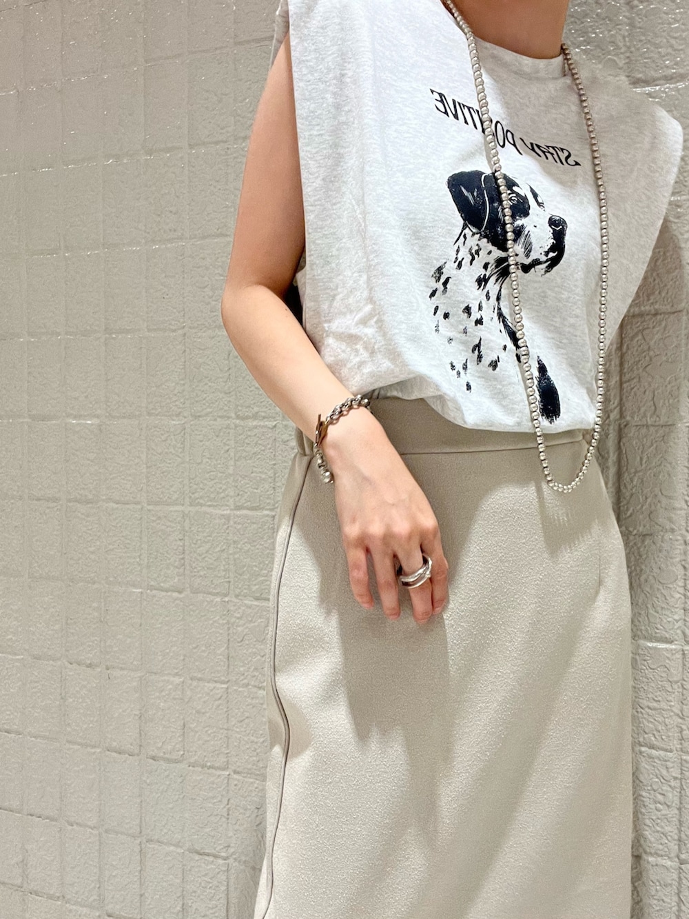 シルバー系のサンダル、ホワイト系のスカート、グレー系のTシャツ/カットソーを着用したレディースの夏コーディネートの2枚目の写真