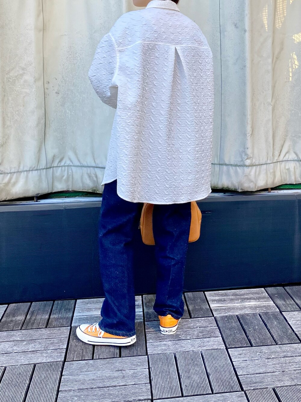 イエロー系のボストンバッグ、オレンジ系のスニーカー、ブルー系のデニムパンツを着用したレディースの冬コーディネートの2枚目の写真