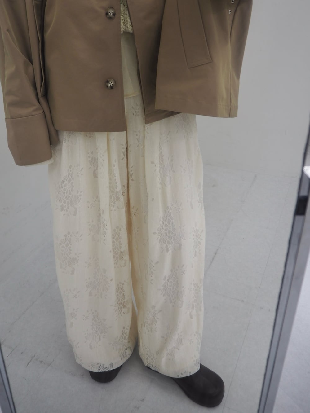 ベージュ系のステンカラーコート、ホワイト系のその他パンツ、ブラウン系のその他シューズを着用したレディースの冬コーディネートの5枚目の写真