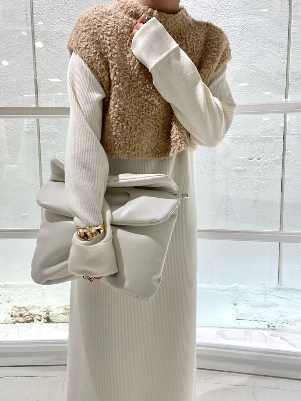 グレー系のブーツ、ホワイト系のワンピース、ブラック系のハンドバッグを着用したレディースの冬コーディネートの3枚目の写真