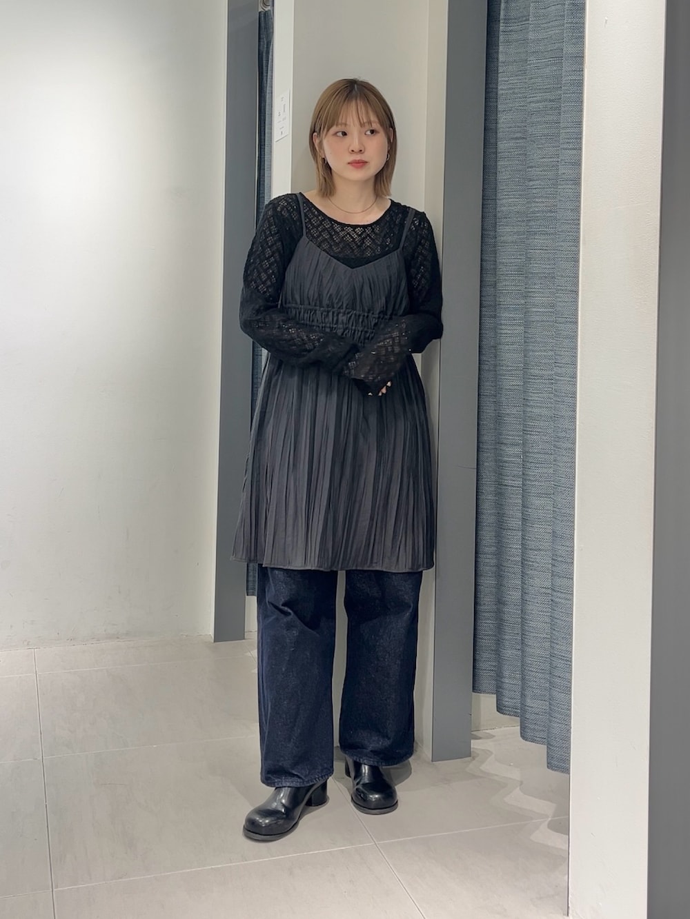 グレー系のワンピース、ブルー系のデニムパンツ、ブラック系のサンダルを着用したレディースの春コーディネートの3枚目の写真