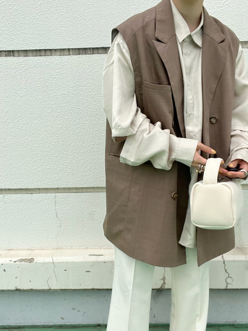 ブルー系のベスト、ホワイト系のハンドバッグ、ブラウン系のシャツ/ブラウスを着用したレディースの春コーディネートの3枚目の写真