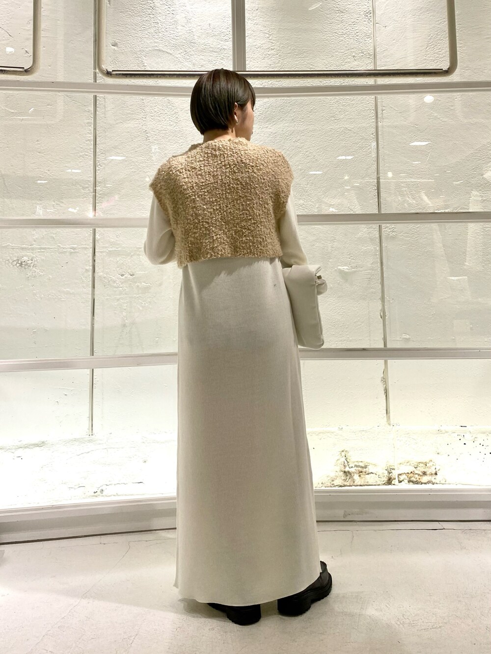 グレー系のブーツ、ホワイト系のワンピース、ブラック系のハンドバッグを着用したレディースの冬コーディネートの4枚目の写真