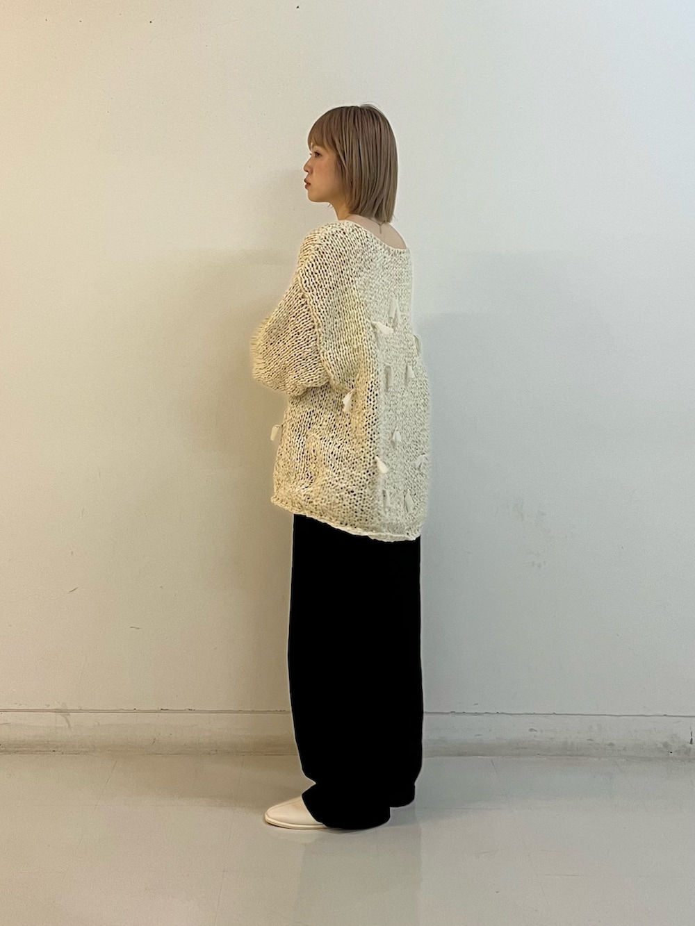 ホワイト系のニット/セーター、ホワイト系のキャミソール、ブラック系のデニムパンツを着用したレディースの冬コーディネートの4枚目の写真