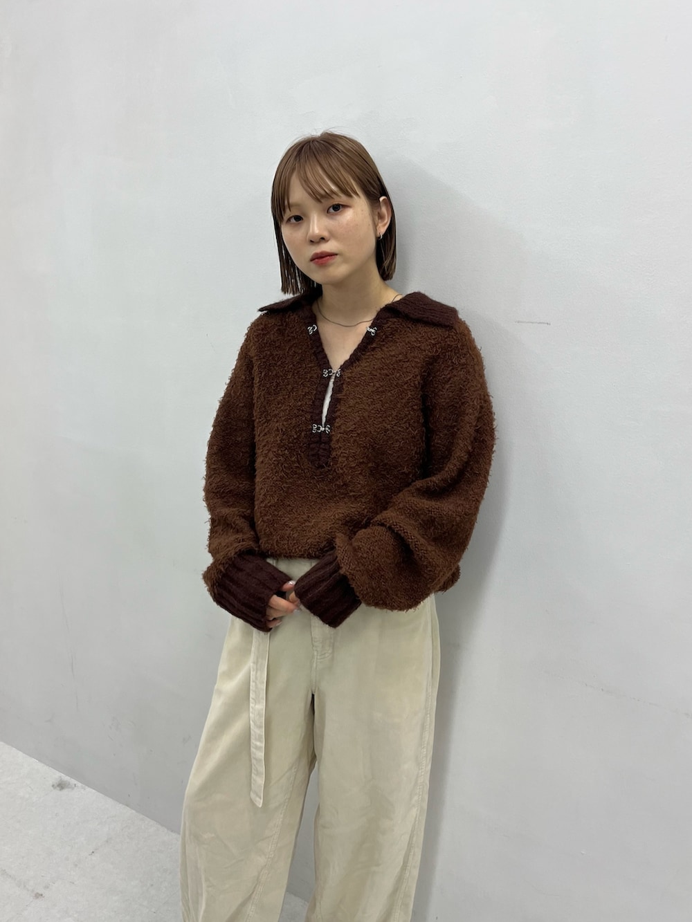 ブラウン系のニット/セーター、ブラック系のブーツ、ホワイト系のその他パンツを着用したレディースの秋コーディネートの2枚目の写真