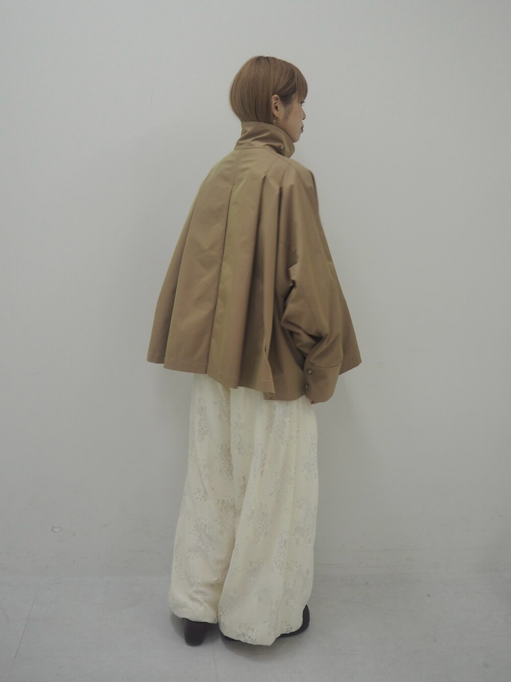 ベージュ系のステンカラーコート、ホワイト系のその他パンツ、ブラウン系のその他シューズを着用したレディースの冬コーディネートの2枚目の写真